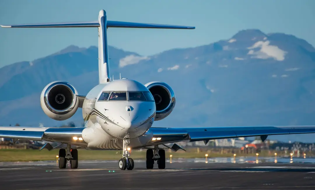 Private jet on a runway with a scenic mountain backdrop